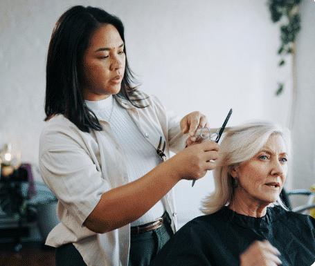 A hair stylist cutting a client's hair in her salon